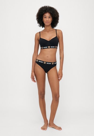 Μαύρο σετ εσωρούχων αποτελούμενο από bralette και μίνι μποξεράκι, και οι δύο με λογότυπο και εκτύπωση αρκούδας. Απαλή ύφανση, μινιμαλιστικός σχεδιασμός.