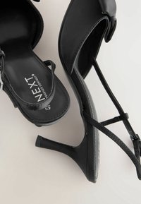 Sandales à talons hauts noires avec fines brides et boucle à la cheville, avec la marque "NEXT Forever Comfort" et taille 6,5/7.