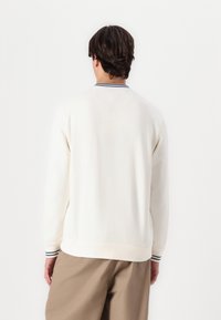 Mikina s kulatým výstřihem v off-white barvě, vyrobená z bavlněné směsi. Vybavena žebrovaným límcem s námořnickou a bílou pruhovanou kombinací. Volný střih s dlouhými rukávy.