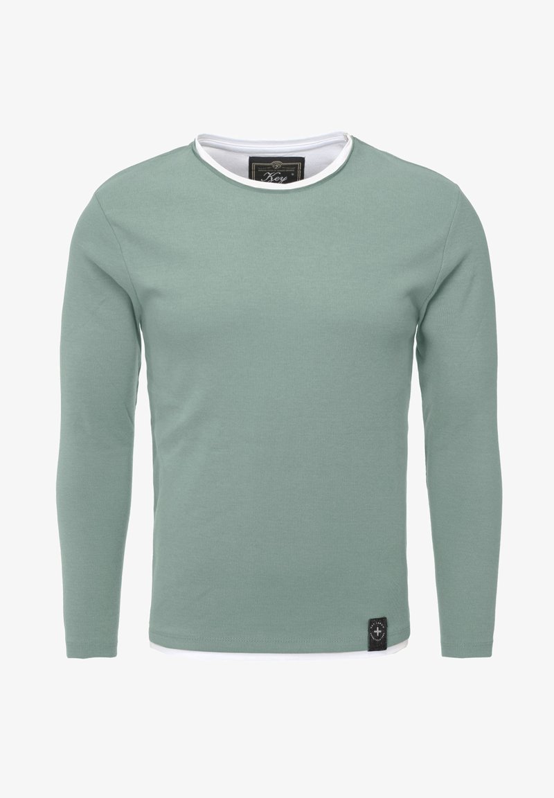 T-shirt a maniche lunghe in cotone verde chiaro con colletto tondo bianco e un'etichetta nera con il marchio nella parte inferiore sinistra. Texture liscia.