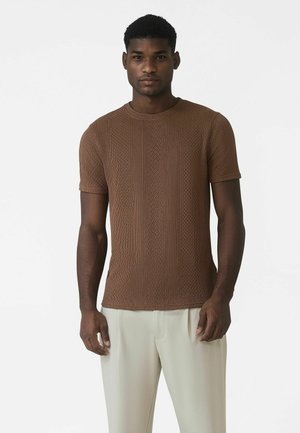 Kortærmet, brun strikket t-shirt med et tekstureret mønster af lodrette linjer. Rund halsudskæring og tætsiddende design.