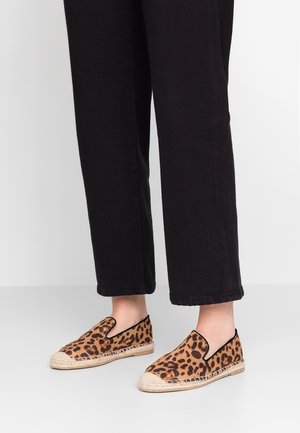 Leopardikuosiset liukupohjaespadrillikengät, joissa on kudottu juteepohja ja musta reunus, yhdistetty mustiin lyhyisiin housuihin. Pehmeä tekstuurinen kangas.