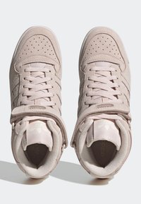 Light pink suede high-top sneakers with perforated details, flat laces, and velcro strap featuring a logo on the tongue and side.