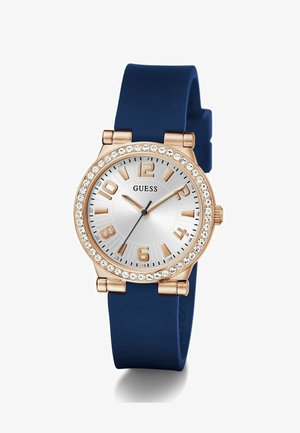 Reloj de oro rosa con esfera plateada, correa de silicona azul, adornos de cristal alrededor del bisel, grandes marcadores de horas y manecillas azules.