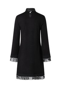 Robe noire à manches longues, avec un col montant et une ouverture en forme de clé au dos. Ourlet et manches ornés de détails en frange texturée.