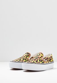 Sneakers slip-on con stampa leopardata, tomaia in tela, macchie gialle e nere, suola in gomma bianca e trim nero a contrasto.