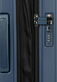 Hartschalentrolley in Dunkelblau, ausgestattet mit einem doppelt zippbaren Reißverschluss, einem TSA-Kombinationsschloss und einer strukturierten Oberfläche für bessere Griffigkeit und Langlebigkeit.