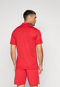 Rode T-shirt gemaakt van een katoenmix, met een polo-kraag, korte mouwen en witte accentstrepen op de schouders. Gecombineerd met bijpassende shorts.