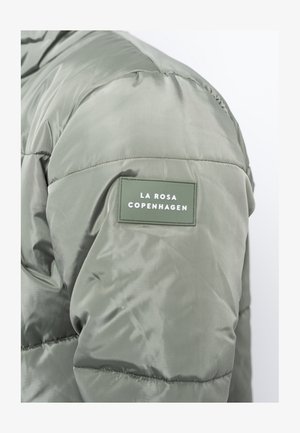 Lichtgroene pufferjack met een gequilt textuur en een onderscheidend groen label met witte tekst die "LA ROSA COPENHAGEN" leest.
