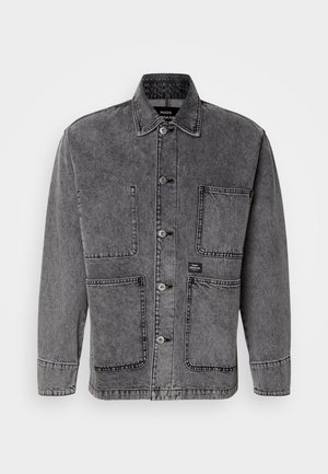 Szara kurtka dżinsowa z kołnierzykiem, zapinana na guziki z przodu oraz wieloma kieszeniami. Widoczne przeszycia i metka z logo podkreślają design.