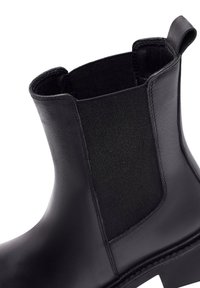 Bottines en cuir noir avec des panneaux élastiques sur les côtés, une finition lisse et une semelle robuste avec un design de bout carré.