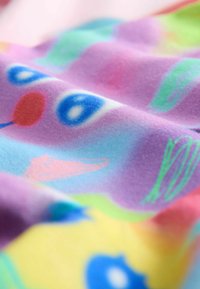 Bunt bedruckter Stoff mit einer weichen Textur zeigt abstrakte Formen in Pink, Blau, Grün und Gelb und erzeugt ein verspieltes, lebhaftes Muster.
