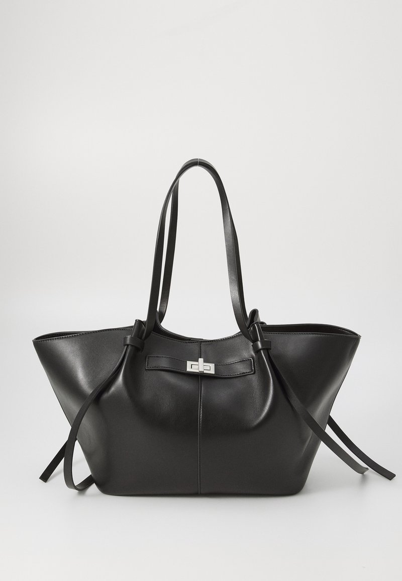 Mala tote de couro preto com uma forma triangular ampla. Apresenta um fecho metálico elegante, alças longas e uma textura suave.