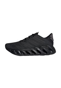Black athletic shoe with a textured mesh upper, three side stripes, and a cushioned sole featuring distinct cutouts for support and flexibility.