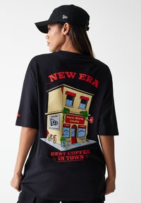 Black oversized t-shirt featuring a colorful café graphic with "New Era" text and "Best Coffee in Town" slogan. Short sleeves, cotton material.