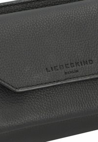 Czarny skórzany portfel o fakturowanej powierzchni, z klapką do składania i wytłoczonym logo "LIEBESKIND BERLIN". Subtelne przeszycia.