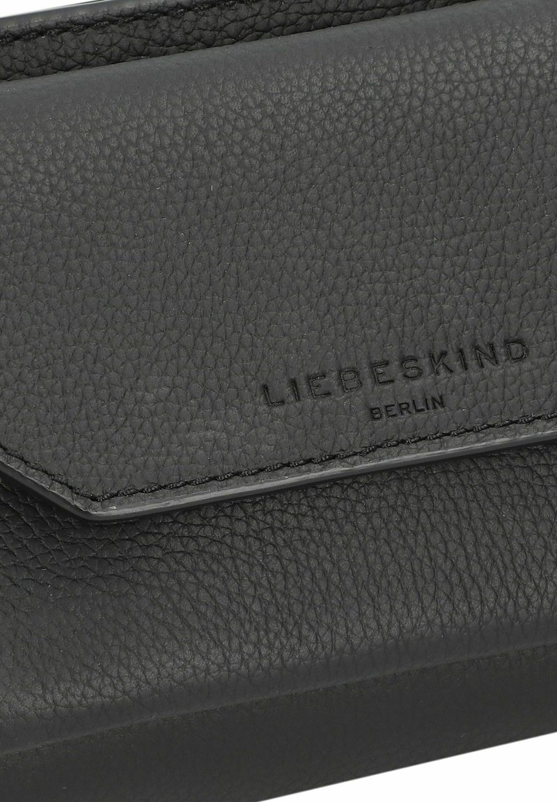 Schwarzes Lederportemonnaie mit strukturiertem Finish, ausgestattet mit einem dreieckigen Klappenverschluss und geprägtem Branding. Die Nähte sind entlang der Kanten sichtbar.
