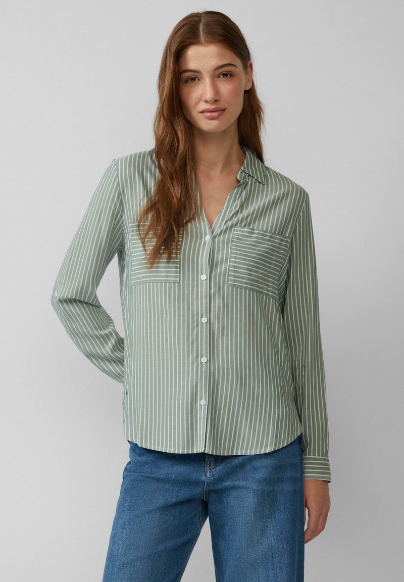 Chemise boutonnée à manches longues vert clair avec des rayures verticales blanches. Présente une poche poitrine et un ourlet inférieur arrondi. Texture de tissu douce.
