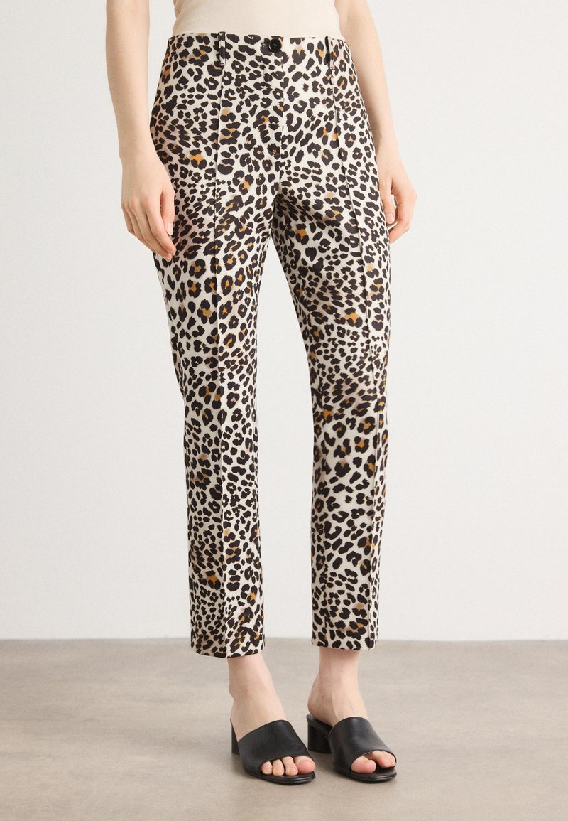 Pantalons en imprimé léopard en tissu léger avec une coupe ajustée, présentant des nuances de noir, marron et crème, associés à des talons ouverts noirs.