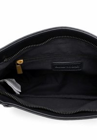 Wnętrze czarnej skórzanej torebki o gładkiej strukturze, wyposażone w kieszeń na suwak, materiałową podszewkę oraz złote elementy zamka.