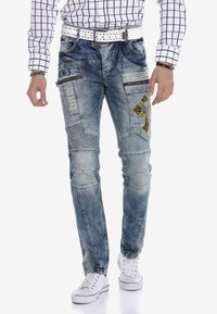Hellblaue Jeans aus Denim mit einem used Look, dekoriert mit gestickten Akzenten, mehreren Taschen und einem schmalen Schnitt.