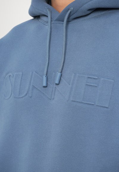 Hooded sweatshirt v svetlo modri barvi, izdelan iz mehkega blaga. Ima diskretno vtisnjen logotip "SUNNEI" in usklajene vrvice.