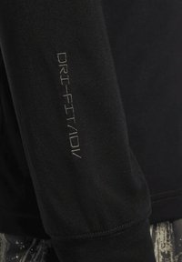 Svart långärmad t-shirt med DRI-FIT ADV-logotyp i reflekterande silver på ärmen, tillverkad av ett mjukt och lätt tyg.