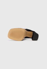 Pantof de damă negru din suede cu toc, cu o talpă din cauciuc texturat, toc pătrat și finisaj neted. Partea de jos are un model cu striații pentru aderență.