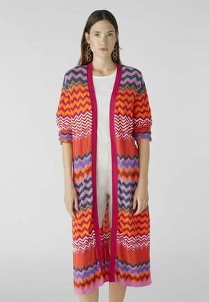 Colorful knitted cardigan featuring a zigzag pattern in red, pink, orange, and green, with a long, open-front design and cuffed sleeves.