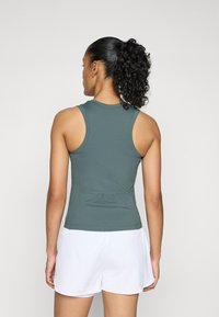 Sportos tanktop sötétzöld bordázott anyagból, testhezálló szabással és kerek hátkivágással. Fehér sorttal párosítva, amely testreszabott fazonú.