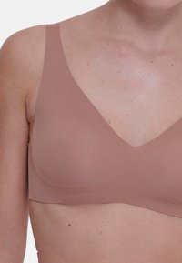 Wyściełany biustonosz braletka z miękkiego, elastycznego materiału z dekoltem w kształcie litery V. Posiada cienkie ramiączka i bezszwowy design w odcieniu nude.