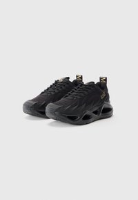 Pair of black athletic sneakers with textured mesh upper, sculpted sole with cutouts, and gold branding on side and heel tab.