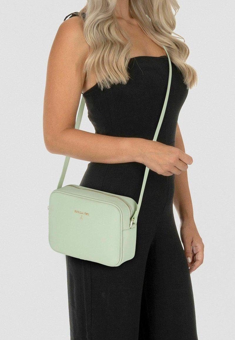 Borsa a tracolla verde menta in pelle liscia. Presenta dettagli in metallo color oro e una chiusura con cerniera, con forma rettangolare e tracolla sottile.