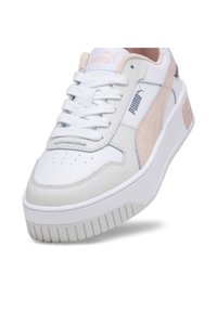 Sneaker bianco con tomaia in pelle texture, accenti rosa e una suola spessa e scanalata. Presenta lacci e un logo laterale.