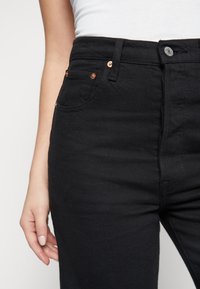 Svarta högmidjade jeans i denim, med koppardetaljer, två framtida fickor och en figurnära design.