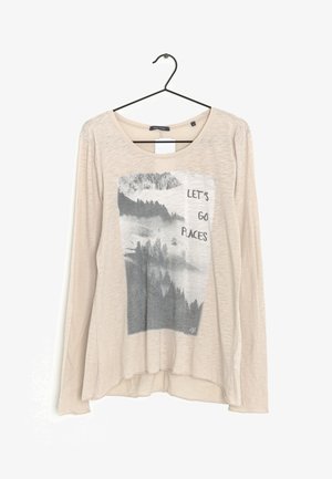 Camisa beige de manga larga con cuello redondo. En el frente presenta un gráfico en gris de un paisaje montañoso y el texto "LET'S GO PLACES." Textura suave.