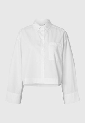 Camicia corta bianca realizzata in tessuto leggero e semplice. Presenta una chiusura con bottoni sul davanti, colletto, maniche lunghe e una tasca sul petto.