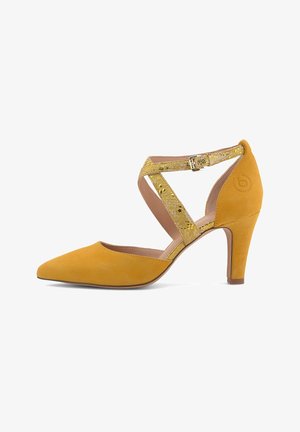 Zapato de tacón alto de ante amarillo con puntera puntiaguda, que presenta correas decorativas doradas y cierre de hebilla en el tobillo para un ajuste seguro.