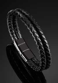 Black braided leather bracelet featuring a sleek silver clasp, embossed with "SERASAR," against a dark gradient background.