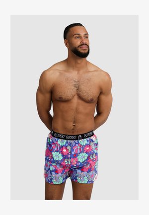 Men's swim shorts featuring a colorful floral and cartoon design, primarily in shades of blue, pink, and green. Black elastic waistband.