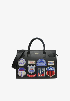 Sort lædertaske med dobbelt håndtag, dekoreret med farverige Paris-tema patches og en aftagelig skulderrem.
