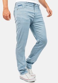 Lichtblauwe gestreepte jeans met een slim fit, vijf-pocket ontwerp en een knoop- en ritssluiting, gecombineerd met witte sneakers.