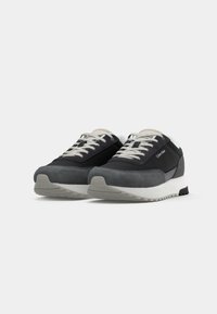 Pair of black and gray Calvin Klein sneakers with white soles and light gray laces on a white background.