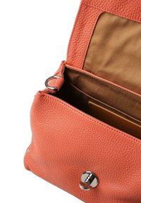 Koraalroze leren handtas met een getextureerd oppervlak, zilveren hardware en een bruin stoffen interieur. Ritssluiting onthult hoofdvak.