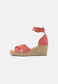Sandalo con zeppa in suede corallo, dotato di cinturino alla caviglia e fibbia dorata, con una piattaforma in juta intrecciata e cinturini incrociati a punta aperta.