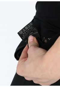 Leggings neri con una texture liscia. Un'etichetta di cura è ben visibile, mostrando le istruzioni di lavaggio e i dettagli del prodotto.