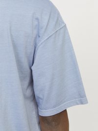 Lyseblå T-shirt med korte ærmer lavet af blødt stof. Viser syningsdetaljer ved halsudskæringen og ærmerne. Afslappet pasform med en glat tekstur.