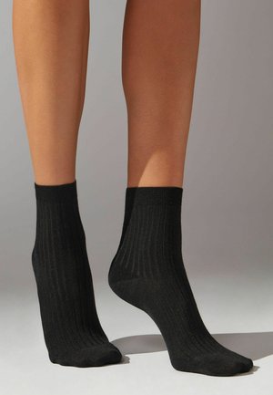 Svarta ankelsockor av ribbad stickad tyg, med en enhetlig färg och en sömlös tådesign. Lämpliga för avslappnad eller vardaglig användning.