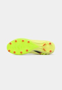 Suela de bota de fútbol de color amarillo brillante con once tacos rojos, y acentos en negro y naranja sobre un fondo blanco.