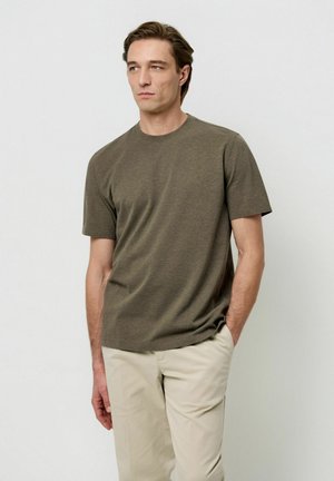 T-shirt girocollo verde oliva scuro realizzata in tessuto morbido e strutturato, abbinata a pantaloni beige chiaro; vestibilità casual con maniche corte.